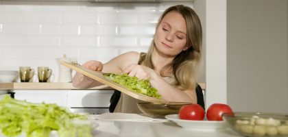 A woman preparing a fresh salad with lettuce and tomatoes in a modern kitchen.