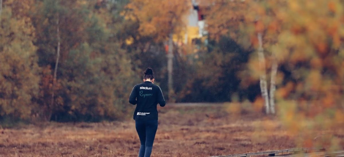 Person jogging on a wooden path surrounded by vibrant autumn foliage in Jönköping, Sweden.