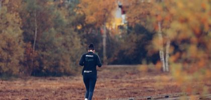 Person jogging on a wooden path surrounded by vibrant autumn foliage in Jönköping, Sweden.