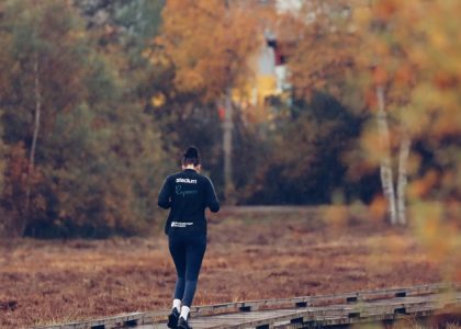 Person jogging on a wooden path surrounded by vibrant autumn foliage in Jönköping, Sweden.